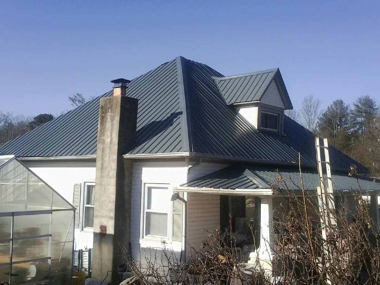 Dark blue standing seam metal roof on a white farmhouse with dormer — Slate & Tile Roof Repair by Roofing Brothers in Mount Joy