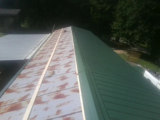 Old rusted panels beside newly installed green metal roofing — Wind Damage Roof Repair by Roofing Brothers in Mount Joy
