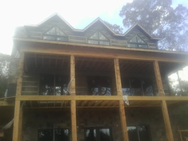 Dormers and porch framing on a large log home under construction — Roof Coating work by our crew in Mount Joy