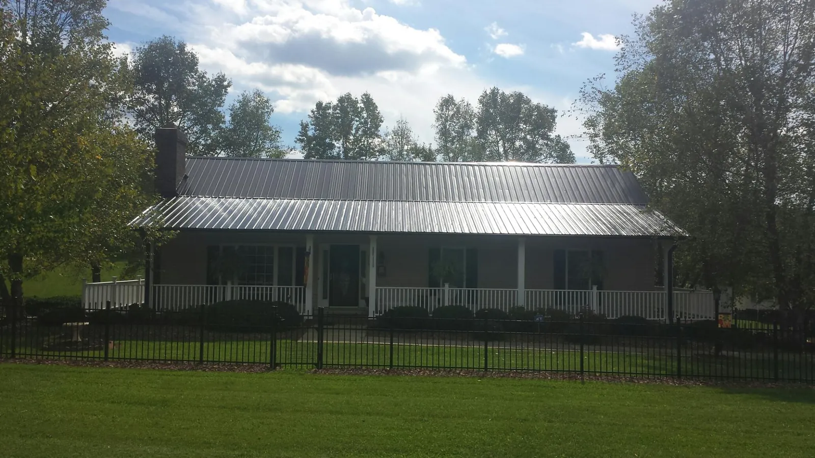 Gray metal roof on a brick ranch with a full width front porch — Gutter Guard Installation work by our crew in Mount Joy