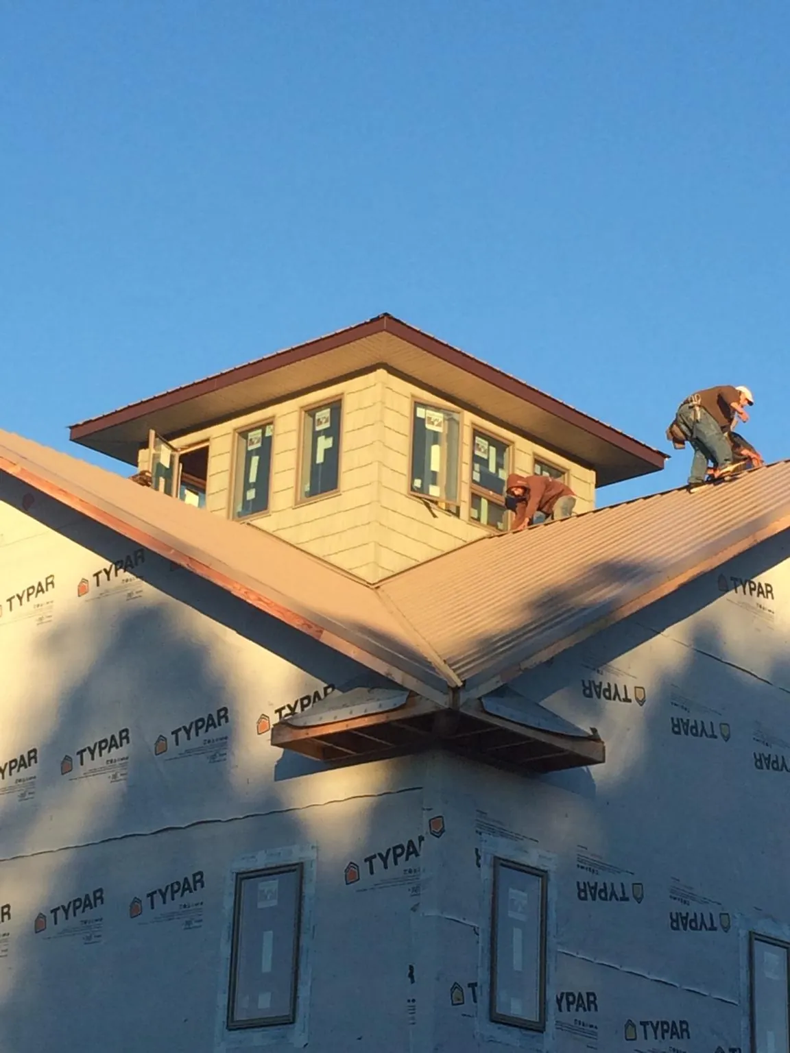 Roofers working around a rooftop cupola on a new metal roof at sunset — Roof Waterproofing in Mount Joy by Roofing Brothers